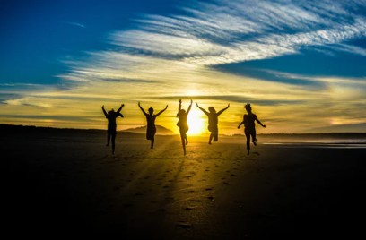 People jumping on the beach with a sunset