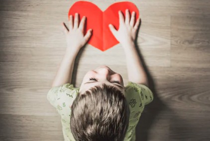 Kid holding a red heart from paper