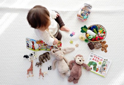 Baby sitting on a white sheet with toys around him